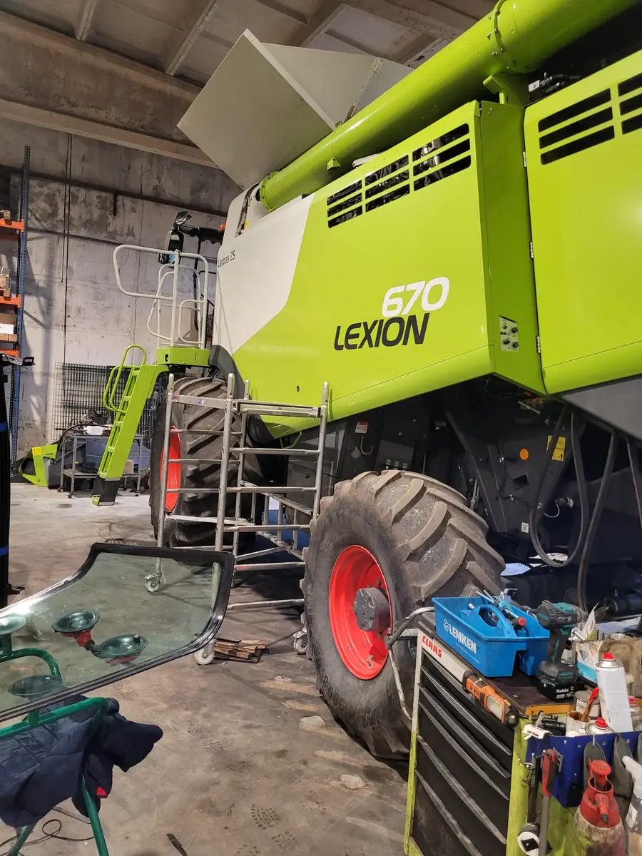 Claas Lexion kombains darbnīcā pirms kabīnes stikla maiņas
